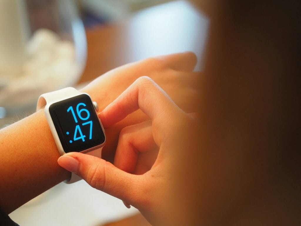 Una persona que opera un reloj inteligente digital que muestra la hora con una interfaz azul.