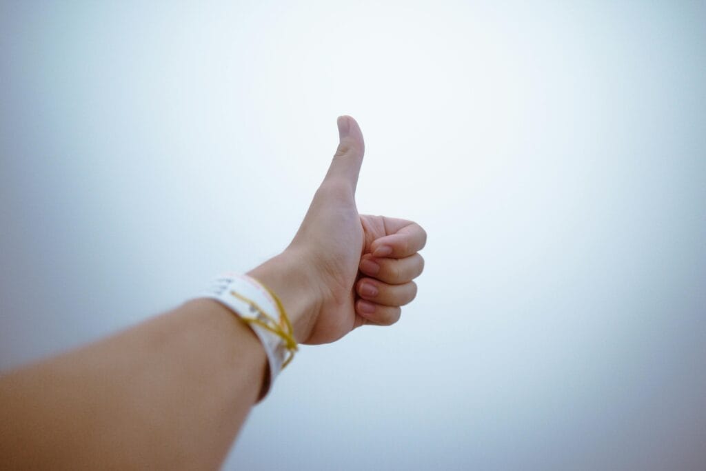 Una mano que da un gesto de pulgar hacia arriba simboliza aprobación y positividad.