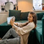 Una joven se relaja en un sofá mientras se toma un selfie, capturando un momento de ocio en el interior.